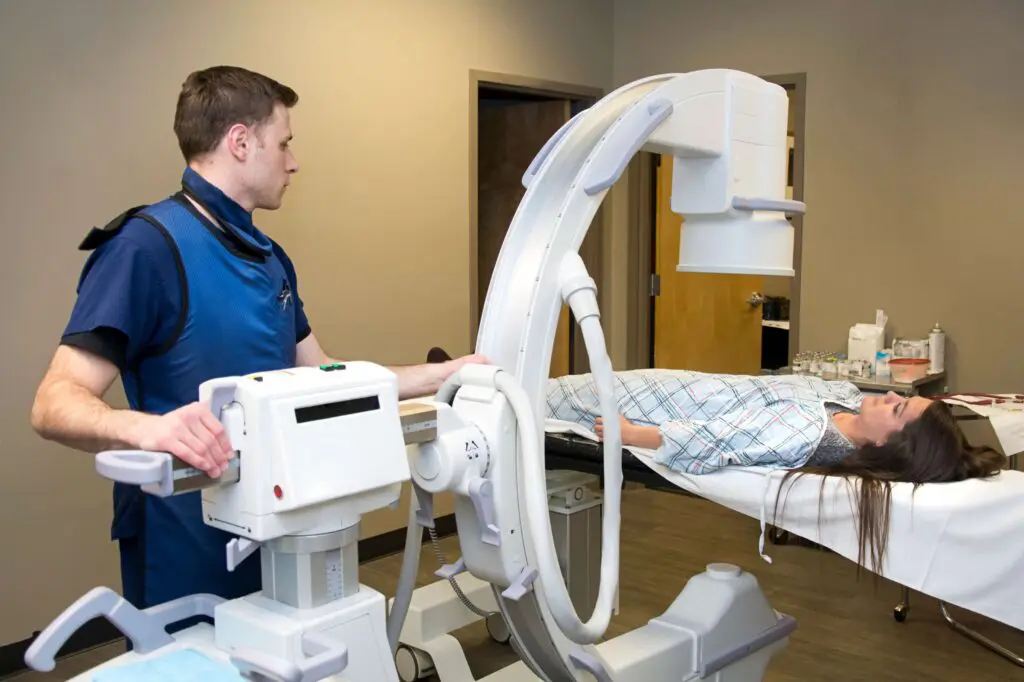 Technician operating medical imaging equipment on patient.